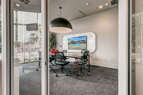 A conference room with a table, chairs and a screen on the wall.